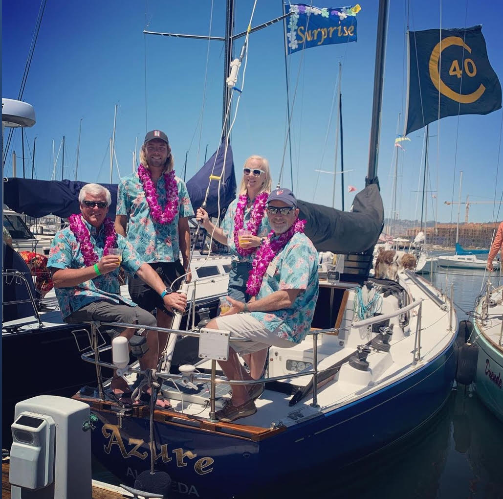 People in matching aloha shirts and leis posing on a sail boat